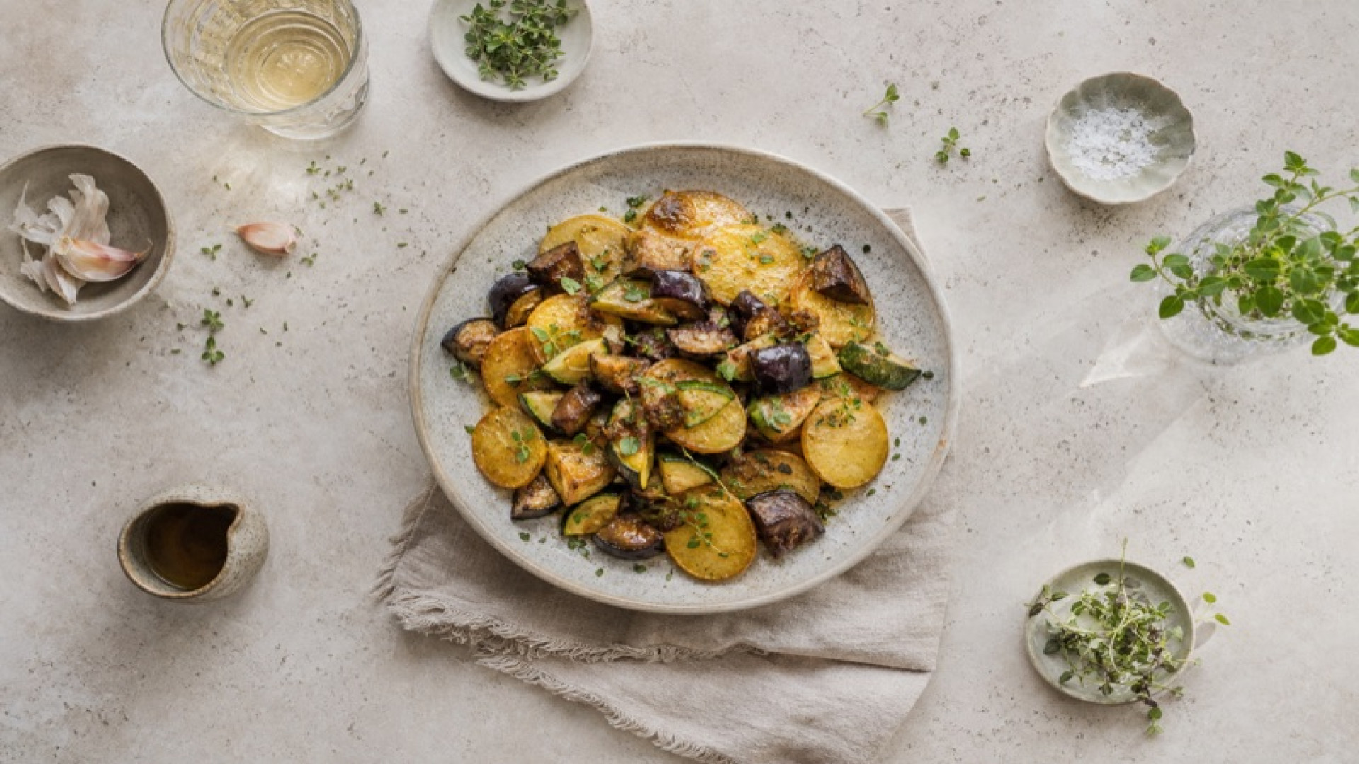 Goldbraune Kartoffelscheiben mit geschmorter Aubergine und Zucchini