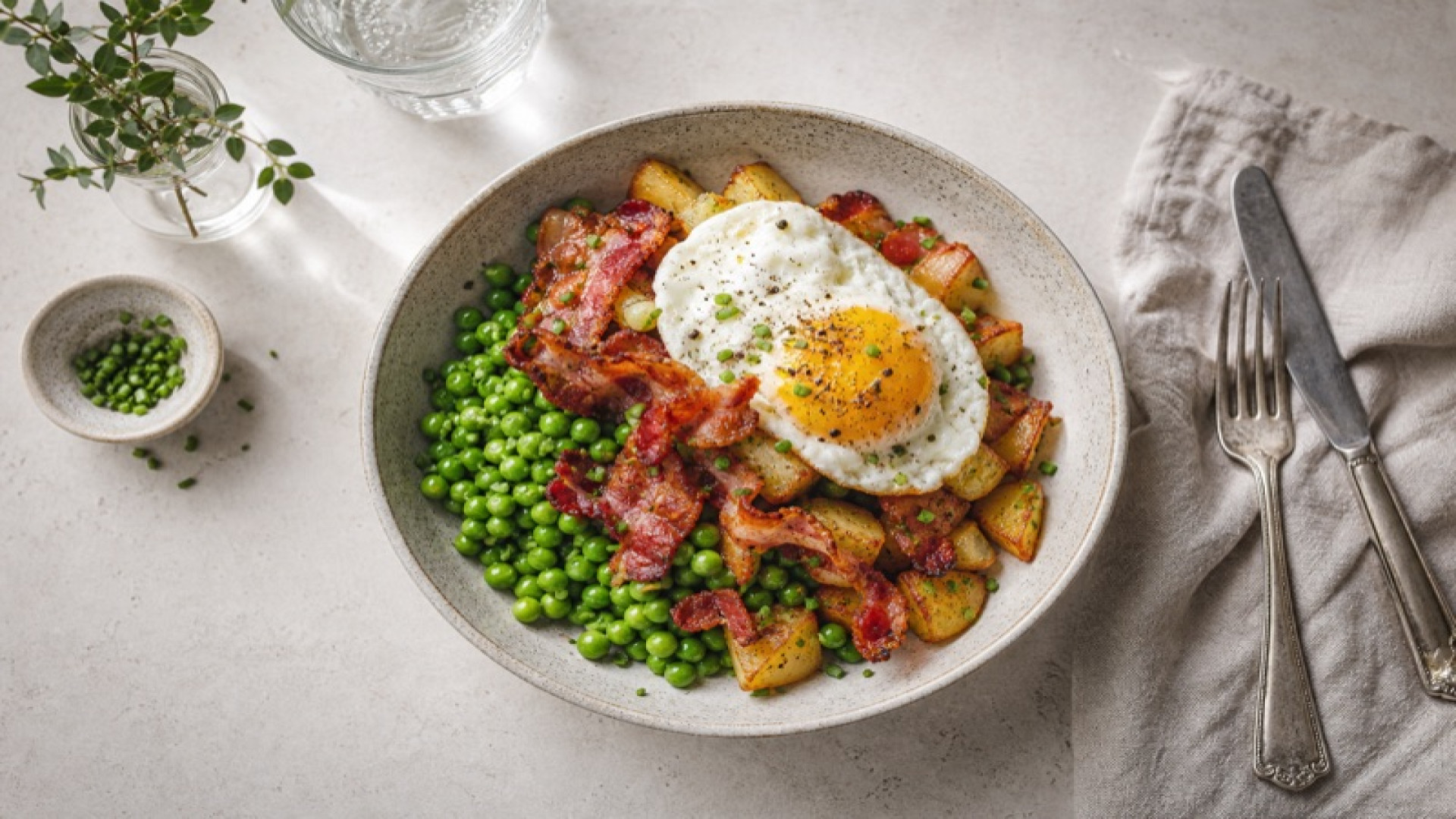Knuspriger Frühstücksspeck-Kartoffel-Bowl mit gedünsteten Erbsen
